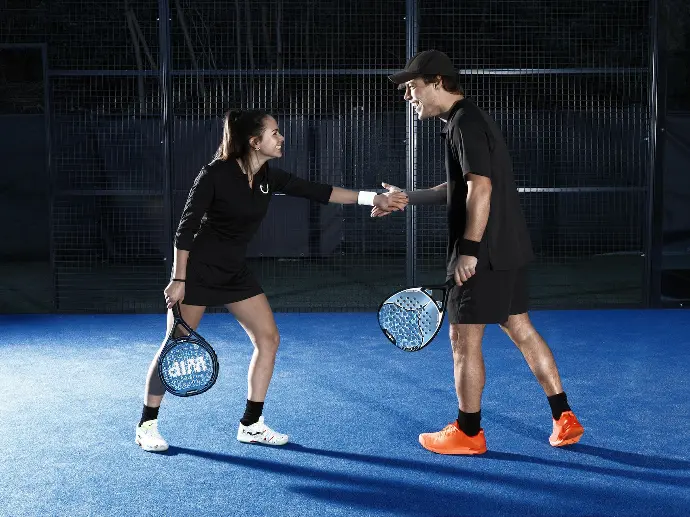 a man and woman shaking hands on a tennis court